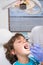 Pediatric dentist examining a little boys teeth in the dentists chair