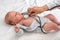 Pediatric doctor examines newborn baby girl with stethoscope