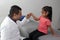 Pediatrician doctor and 4 year old latin girl patient in consultation are friends and make hi five sign and bump fists