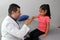 Pediatrician doctor and 4 year old latin girl patient in consultation are friends and make hi five sign and bump fists