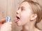 Pediatrician examining elementary age girl sore throat using wooden tongue depressor and torch in pediatric clinic