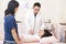 Pediatrician examining little girl on the bed