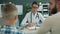 Pediatrician friendly woman speaking with young man and little boy in hospital room