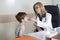 Pediatrician Giving Cough Syrup To Sick Boy In The Consulting Room