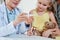 Pediatrician showing thermometer to girl