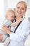 Pediatrician is taking care of patient in hospital. Female doctor holds toddler girl at hands