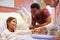 Pediatrician Visiting Father And Child In Hospital Bed