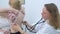 Pediatrician woman listening to heartbeat of girl using stethoscope in clinic.