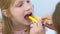 Pediatrician woman looking child girl sore throat using spatula and lantern.