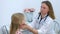 Pediatrician woman probing lymph nodes on neck of girl child during examination.