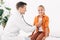 Pediatrist in white coat examining kid with stethoscope