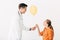 Pediatrist in white coat giving yellow balloon to kid