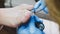 Pedicure master in gloves paints toenails using silver glitters in beauty salon.