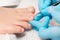A pedicure master in medical gloves takes care of beautiful female toenails. Close-up. The concept of chiropody and