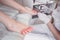 Pedicurist doing white nail polish on client legs using toe finger separator. Professional medical pedicure procedure. Foot