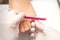 Pedicurist hands in protective rubber gloves filing toenails on feet with a nail file in a beauty salon.