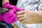 Pedicurist master in pink gloves cuts the cuticle and shellac toe nails in the pedicure salon using drill.  Professional pedicure