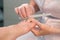 Pedicurist master woman is filing nails on toes using nail file, hands closeup.