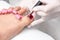 Pedicurist painting red nail polish on female toenail