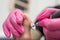 A pedicurist treats the toes of a client using a machine with an abrasive disc in a beauty salon.