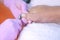 Pedicurist woman cutting toe nails using nippers in beauty salon, closeup view.