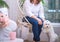 Pedigree white dog lap-dog stands next to a housewife woman sitting in a hanging swing in a home interior