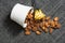 Peeled almonds in a white bowl on grey fabric texture. Spilling nuts flat lay. Yellow flower decorating