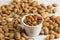 Peeled almonds in a white bowl and nutshell around on beige fabric texture. Background of nuts.