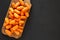 Peeled baby carrots on rustic wooden board on black background, top view. Overhead, from above, flat lay. Copy space