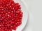 Peeled bright red pomegranate seeds in a white plate