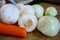 Peeled carrot onions and champignon mushrooms on a wood board in the kitchen. Vegetable products for soup.