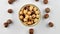 Peeled hazelnuts in a bowl and whole hazelnuts on a white background