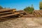 Peeled logs lying in piles on the ground on a sunny day.