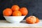 Peeled mandarines and clementines next to a bowl on a white wooden table.