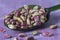 Peeled pistachio nuts in a spoon, isolated, purple wooden background