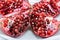 Peeled pomegranate seeds in a cup along with a fraction of fresh pomegranate isolated on white