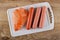 Peeled sausages, polyethylene shell on cutting board on wooden table. Top view