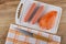 Peeled sausages, shell on cutting board, knife on napkin on wooden table. Top view