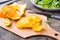 Peeled and sliced orange on a cutting board and a mix of arugula, chard and mizun on a plate on the table.