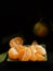 Peeled tangerines with leaves in a dark green dish on a black stone surface. Close-up. Citrus. Copyspace for text