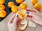 Peeling mandarin. Female hands peel the fresh orange fruit. Citrus fruits lying on the table. Tangerine peel