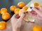 Peeling mandarin. Female hands peel the fresh orange fruit. Citrus fruits lying on the table. Tangerine peel.