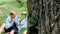 Peeping from behind a tree for a father and two children sitting on a picnic.