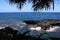 Peering through the trees to a volcanic rock shelf in the Pacific Ocean at Onomea Bay, Papaikou, Hawaii