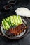 Peking Duck served with cucumber, green onions, and roasted wheaten chinese pancakes with sauce Hoysin. Black background