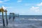 Pelicans on old broken wooden pier in Gulf of Mexico with two birds flying - Copy space