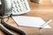 Pen lying on blank white note cards next to a landline telephone