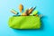 Pencil case with school supplies on blue background