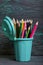 Pencil filled with colored pencils. In the form of a garbage container. Against the background of brushed pine boards painted in