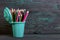 Pencil filled with colored pencils. In the form of a garbage container. Against the background of brushed pine boards painted in